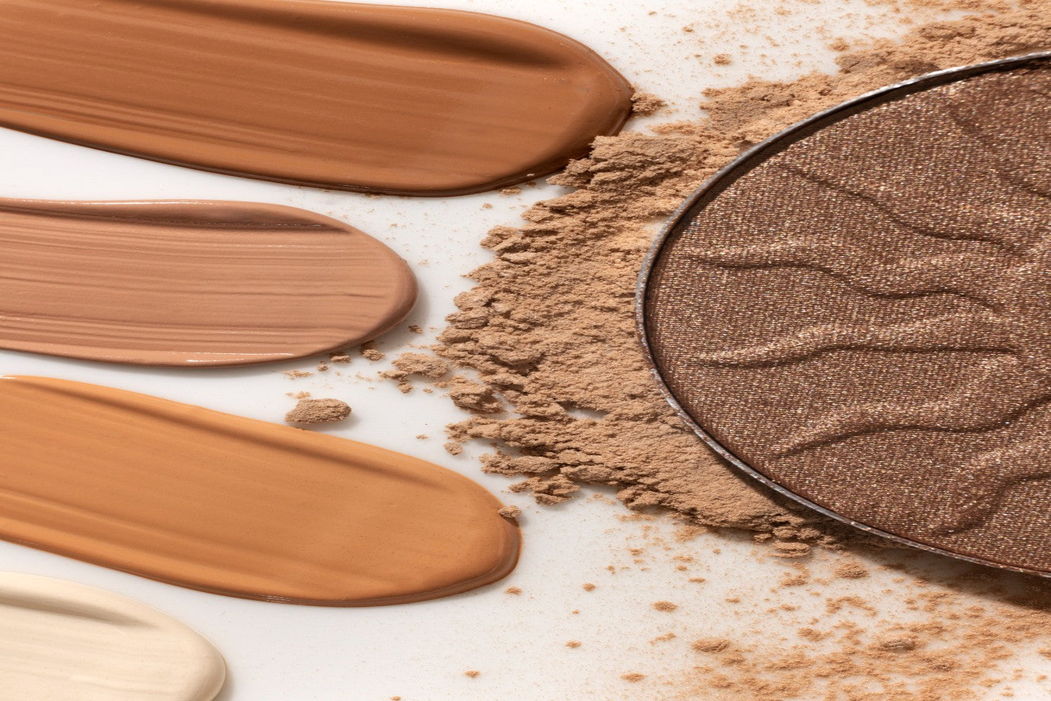 Vista de diversos colores de maquillaje y protector solar con color en polvo y líquidos, sobre un fondo blanco.