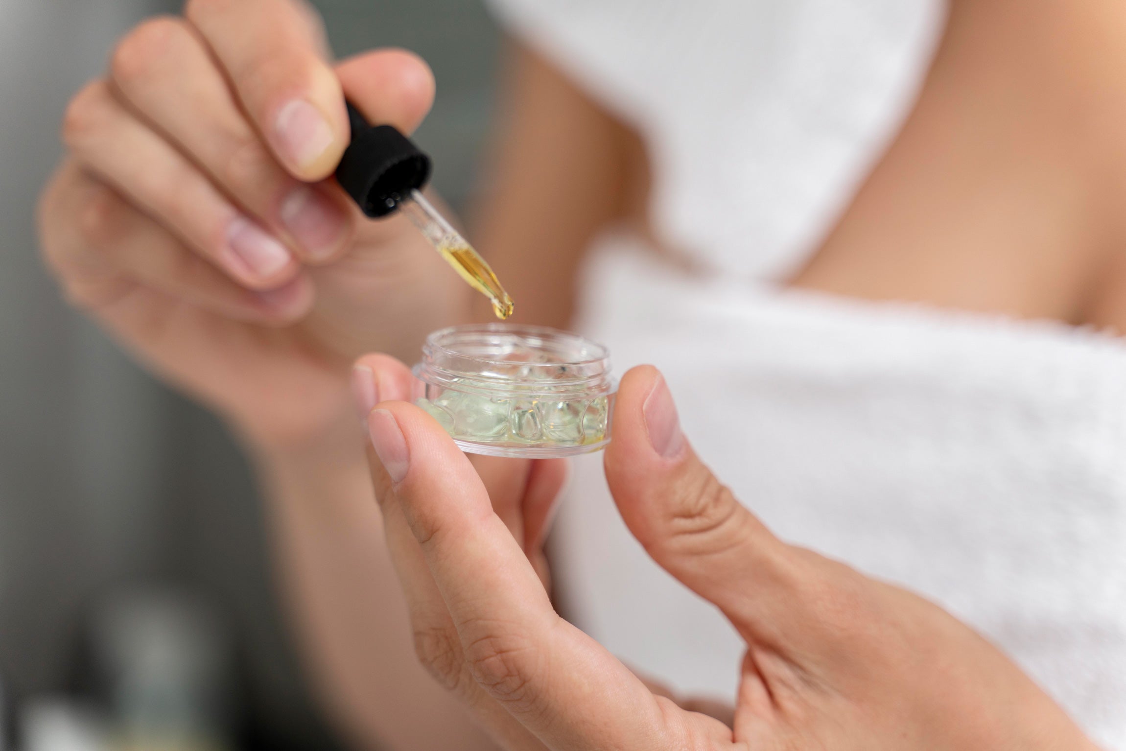 Manos de mujer mezclando un producto de skincare con retinol y otros ingredientes seguros para cuidar la piel correctamente.