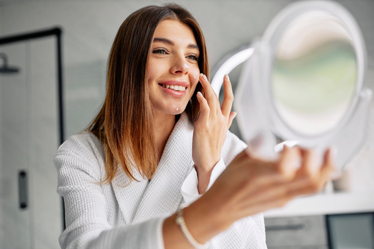 Mujer joven aplicando productos esenciales en su rostro, siguiendo una rutina de skincare minimalista y efectiva.