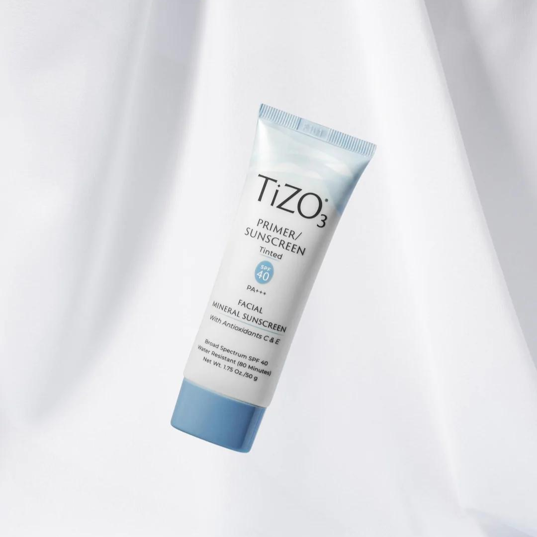 Envase del protector solar mineral Tizo 3 con color, un primer sunscreen con SPF 40 con acabado mate, suspendido sobre fondo blanco suave.