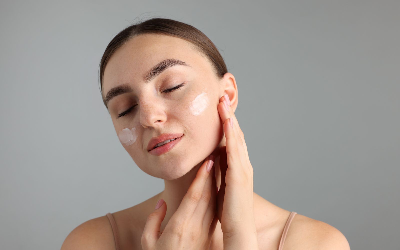 Mujer aplicando crema con probióticos para la piel en su rostro para fortalecer la barrera cutánea y lucir radiante.