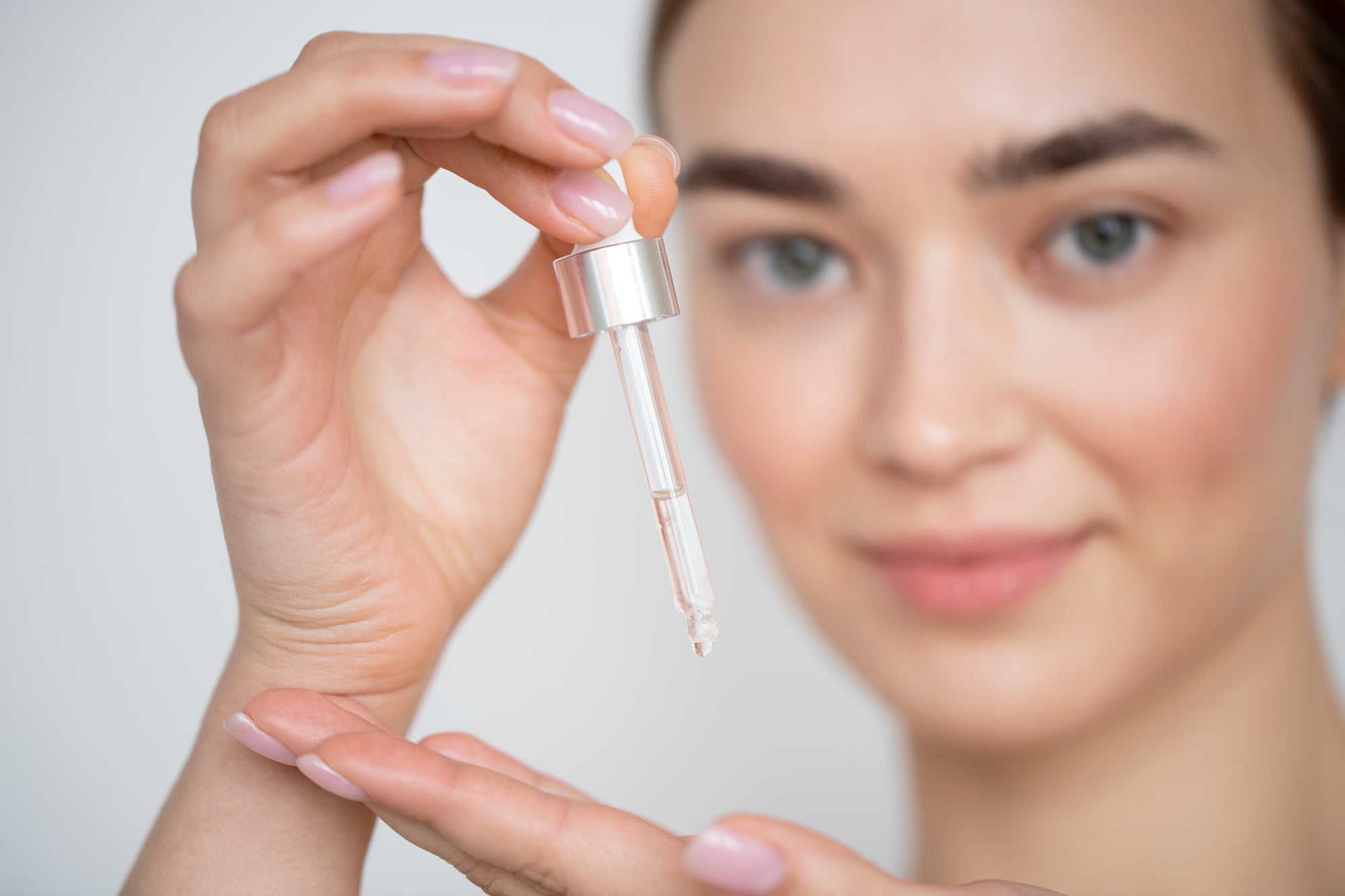 Mujer aplicando sérum con gotero, representando el uso de retinol y retinal en rutinas de cuidado facial