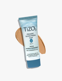 Envase de Tizo 3 con color, protector solar mineral facial sobre un fondo claro con muestra de tono aplicado junto al tubo.