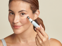 Mujer aplicando Colorescience Total Eye 3 in 1 Renewal Therapy en el contorno de ojos con el aplicador metálico incluido en el envase.
